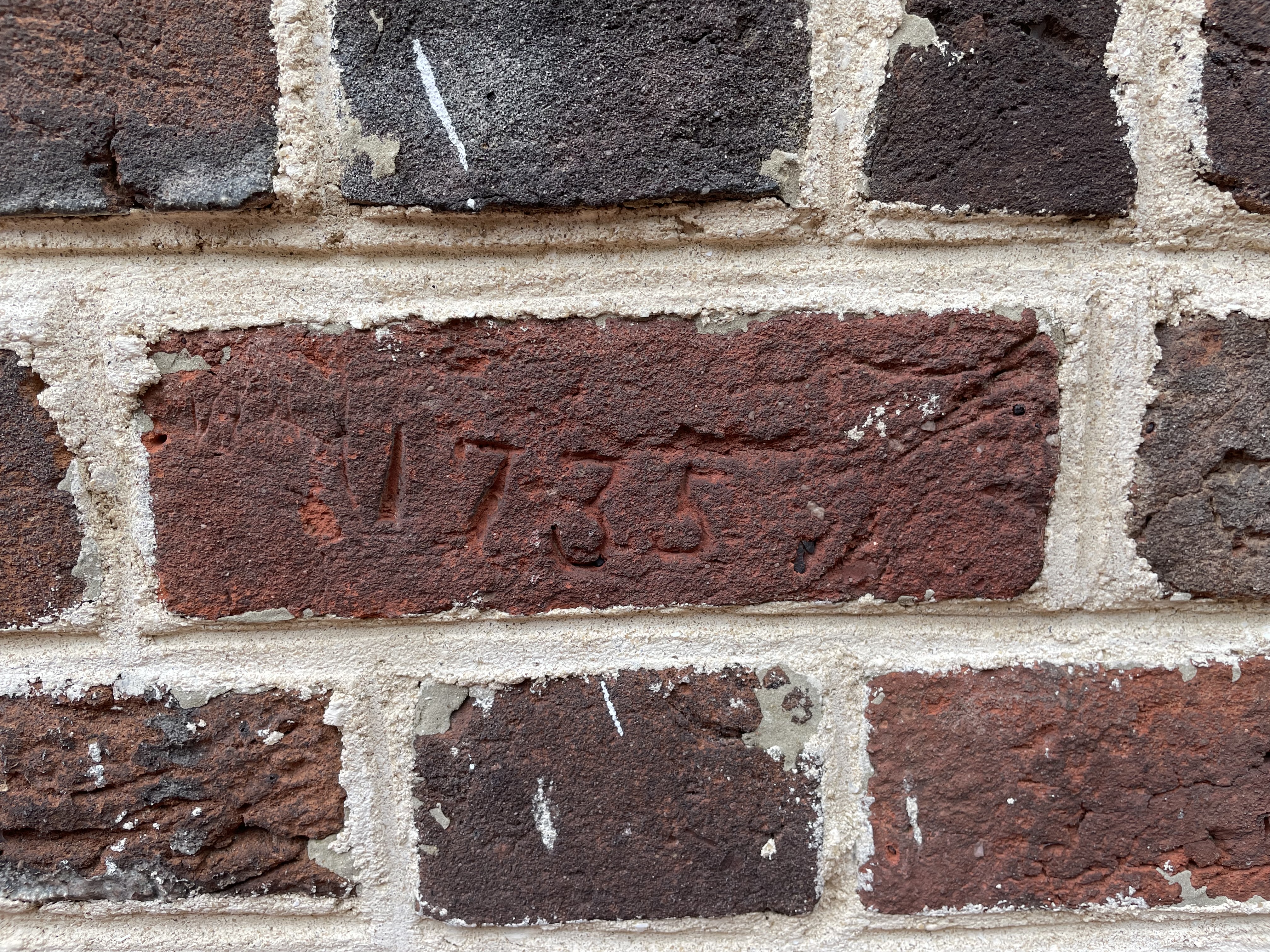 Detail image of a brick wall with a date inscription on a brick face.