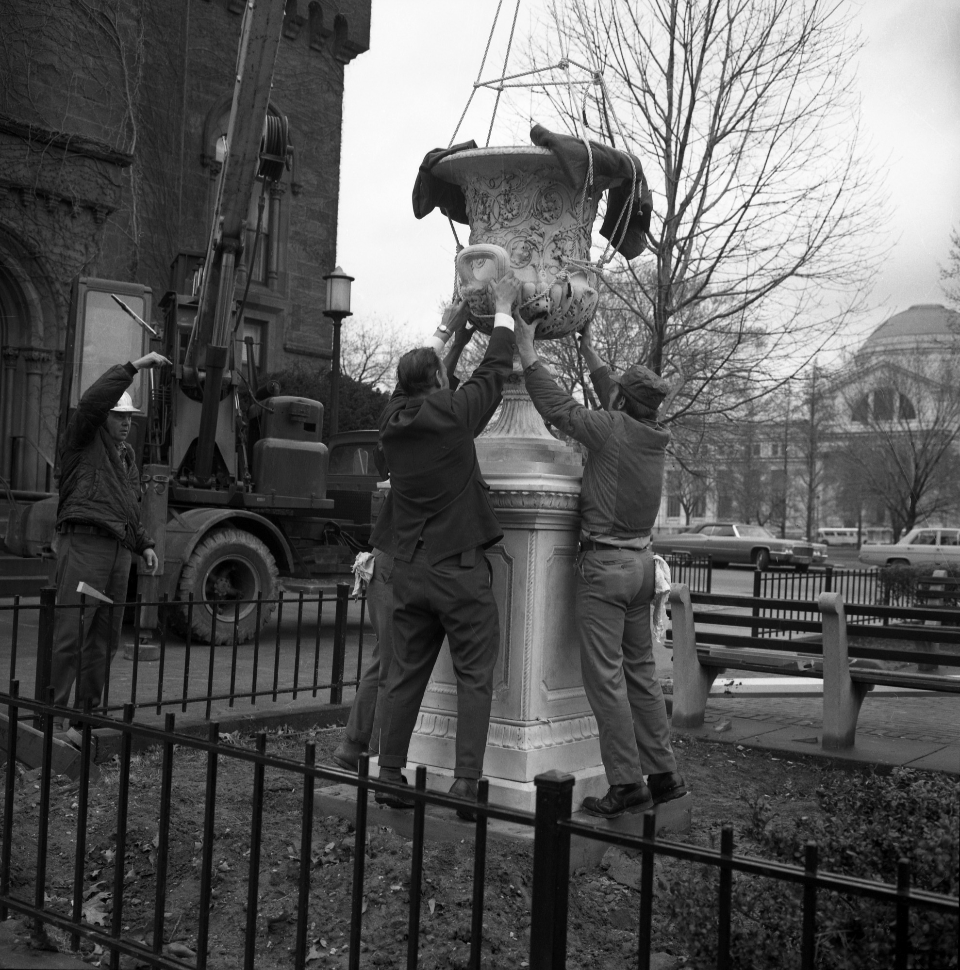 Image of three people placing the Downing Urn on its pedestal.