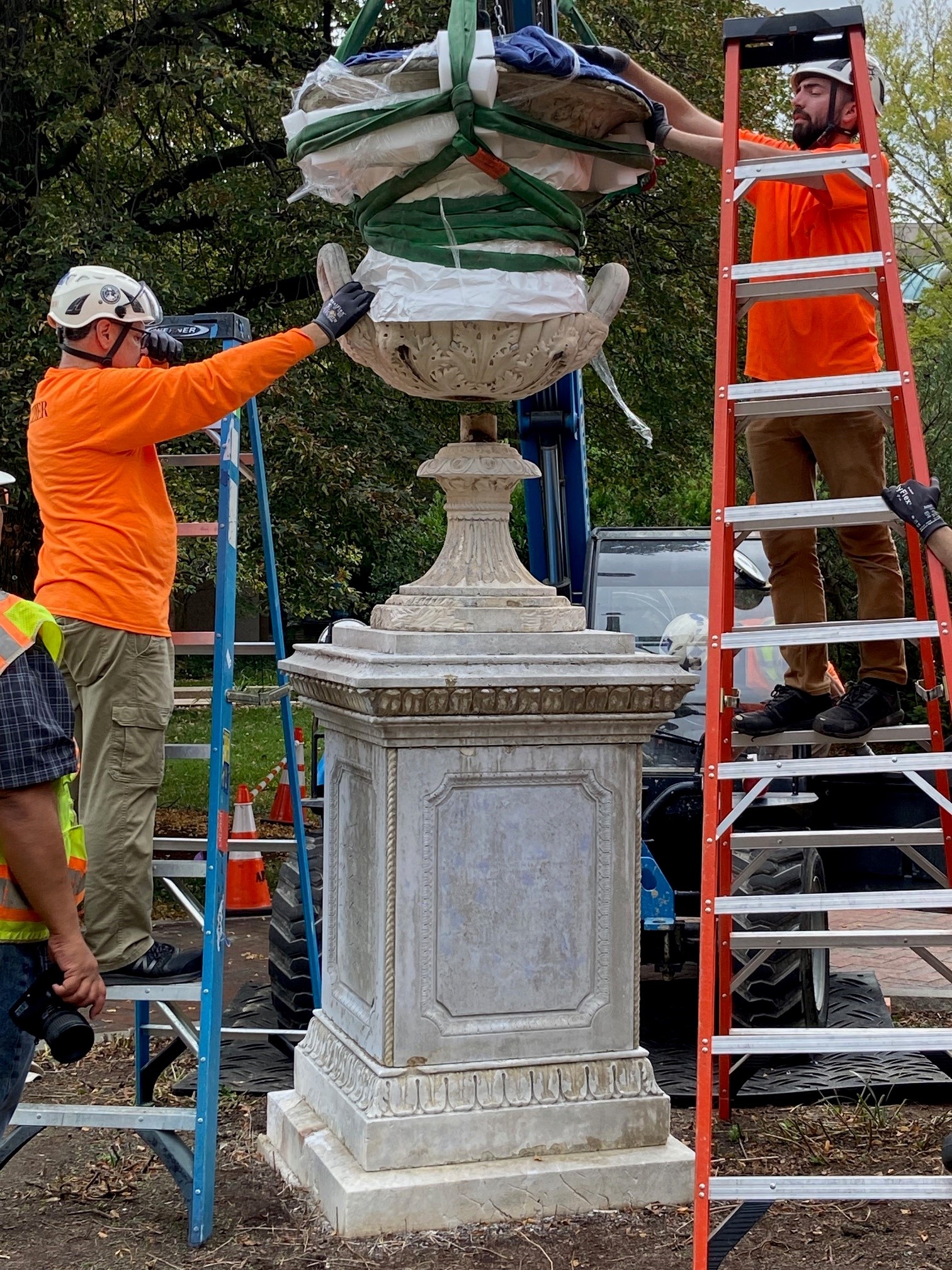 Modern image of people surrounding the Urn with a crane lifting it from its pedestal.