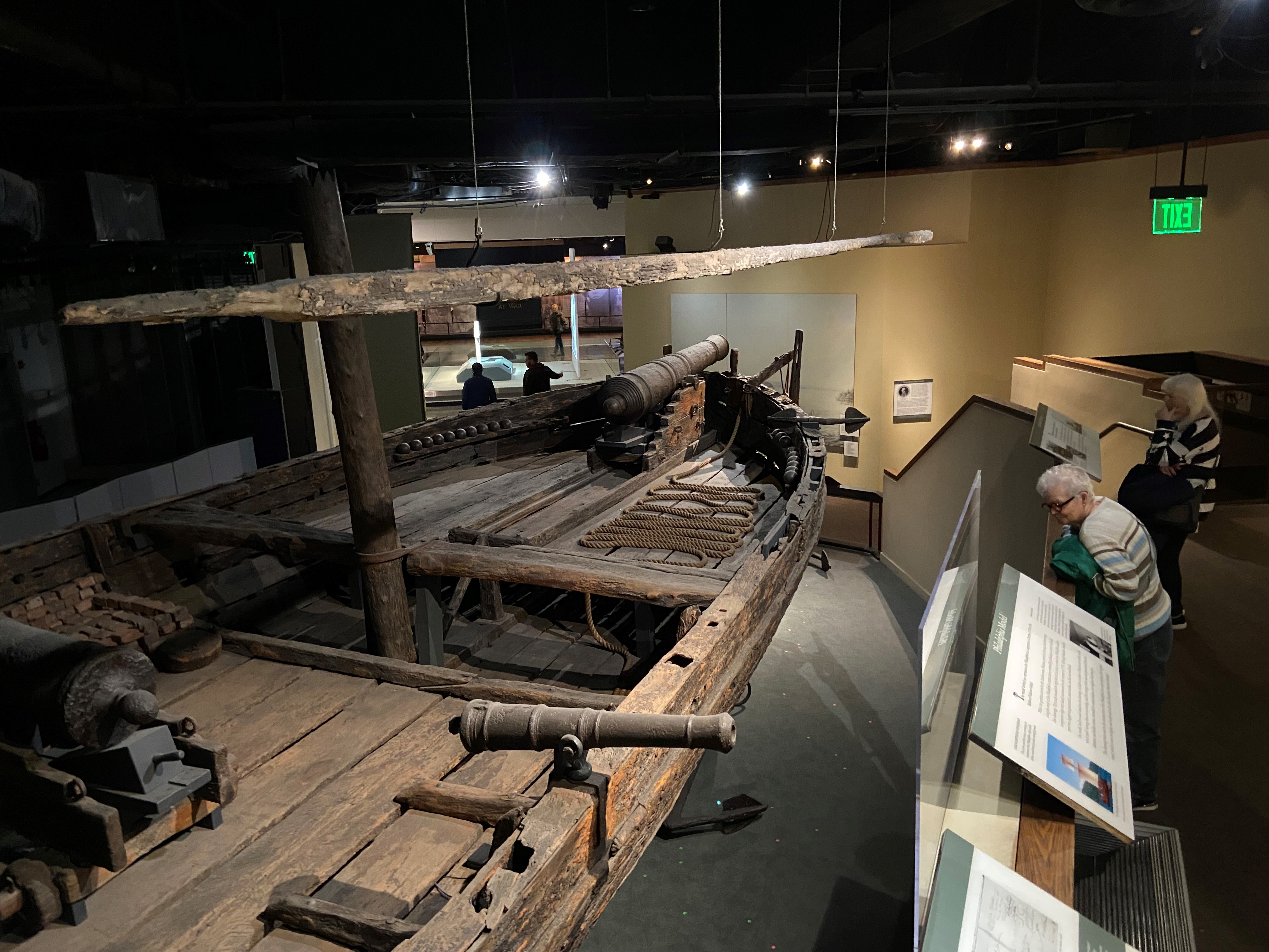 Aerial image of an old wooden boat in a museum setting.