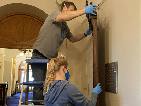 Smithsonian staff removing a decorative frame from an interior wall.